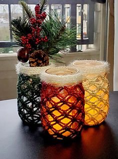 three lit candles sitting on top of a table next to a potted pine tree