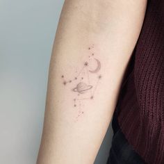 a woman's arm with a small star and moon tattoo on the left forearm