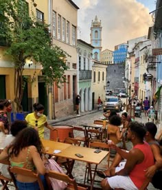 several people sitting at wooden tables in an alleyway