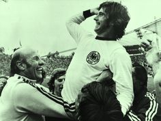 an old photo of a soccer player being carried on his shoulders by two men in the crowd