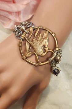 "I created this striking mixed metal bracelet using a rare 1930s Asian Style Art Deco heron stamping as its centerpiece. The stamping has been combined with links from a silvertone vintage chain bracelet, mixed colors of Swarovski crystals, and vintage bead caps.  The stunning centerpiece measures 1 3/4\" across and the bracelet measures 7 1/2\" long.   Our unique assemblage bracelet will make a great gift for Christmas, a birthday or an anniversary....or just buy it for yourself. Please take a Unique Gold Metal Charm Bracelet, Gold Vintage Charm Bracelets For Wedding, Vintage Rose Gold Metal Bracelets, Gold Bracelets With Vintage Charm For Wedding, Victorian Brass Silver Bracelets, Adjustable Metal Bracelet With Vintage Charm, Adjustable Gold Bracelet With Vintage Charm, Adjustable Metal Bracelets With Vintage Charm, Adjustable Gold Bracelets With Vintage Charm