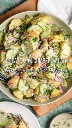 a bowl filled with cucumber salad on top of a wooden cutting board next to two white plates