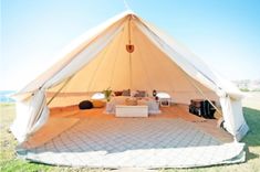 a large tent set up in the middle of a field with chairs and couches