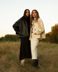 two women standing next to each other in a field