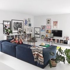 a living room filled with furniture and lots of pictures on the wall next to bookshelves