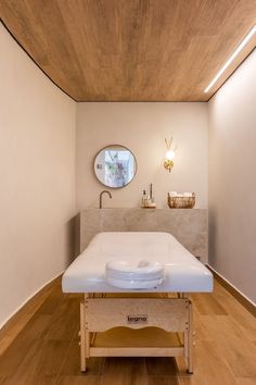 a white bed sitting in the middle of a room next to a sink and mirror