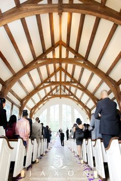 people are walking down the aisle at a wedding in a large building with wooden beams