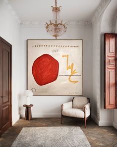 a painting hangs on the wall next to a chair and lamp in a living room