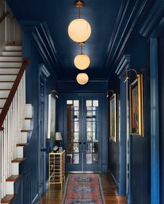 an entryway with blue walls and wooden floors, two lamps on either side of the door