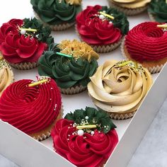 cupcakes decorated with red, green and gold icing in a white box