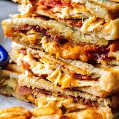 a stack of toasted sandwiches sitting on top of a white plate next to a blue bowl