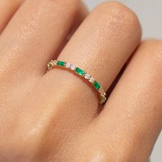 a woman's hand with an emerald and diamond ring