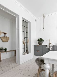 a white kitchen with wooden floors and gray cabinetry in the center, along with an area rug on the floor