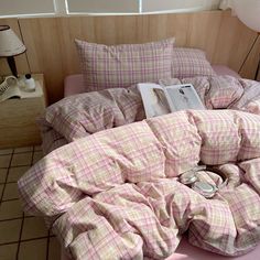 an unmade bed with pink plaid sheets and pillows