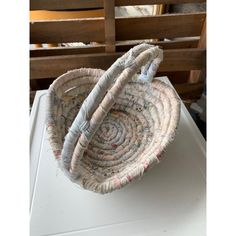 a woven basket sitting on top of a white table next to a wooden chair in the background