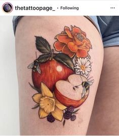 an apple tattoo on the thigh with flowers and leaves around it's core is shown