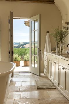 a bath room with a large tub and a door leading to a vineyard area in the background