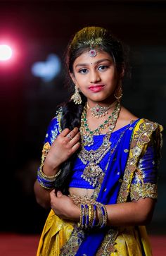 a woman in a blue and yellow sari is posing for the camera with her hands on her chest