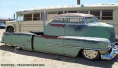 an old green car parked in front of a bus