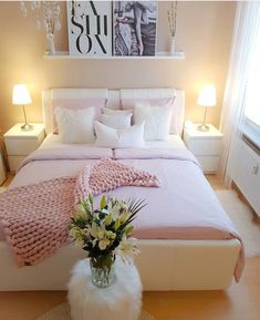 a bed with pink blankets and pillows in a room next to two lamps on either side of the bed