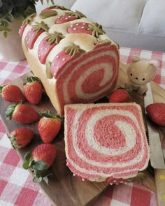 sliced strawberry swirl bread sitting on top of a wooden cutting board next to strawberries