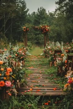 an outdoor ceremony with wooden benches and flowers on the sides, surrounded by greenery