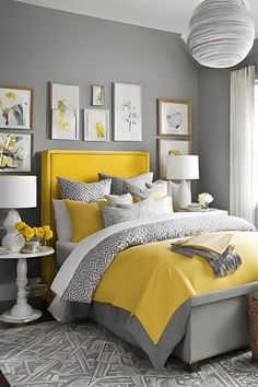 a yellow and gray bedroom with pictures on the wall above the bed, along with lamps