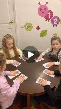 children sitting around a table doing crafts with paper on top of them and one child standing at the end of the table