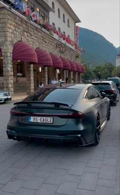 a grey car parked on the side of a road next to a building with red awnings