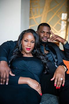 a man and woman sitting on top of a couch next to each other in front of a wall