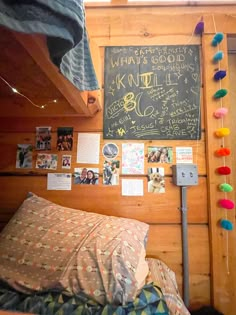 there is a chalkboard on the wall above a bed with many pictures and decorations