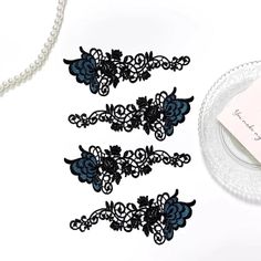 three black lace garters next to a pearl necklace and pearls on a plate