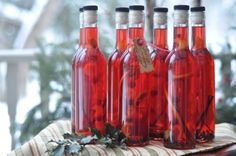 four bottles filled with red liquid sitting on top of a table next to christmas decorations