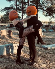 a man and woman dressed up as jack - o'- lanterns in a cemetery