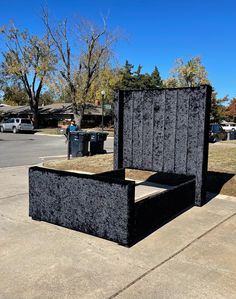 a black bed sitting on top of a sidewalk