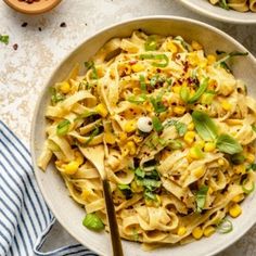 two bowls filled with pasta and vegetables on top of a table