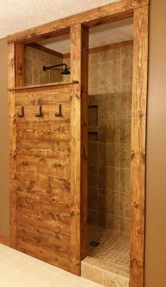 a bathroom with a wooden door and tile flooring in the shower area is shown