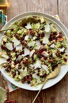 a white plate topped with shaved lettuce and cranberry salad next to christmas decorations