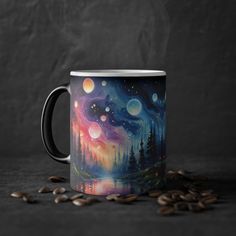 a coffee mug with an image of the night sky and stars on it, surrounded by coffee beans