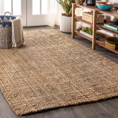 an area rug is shown in front of a wooden table and bookshelf with plants on it