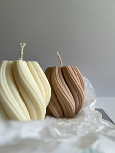 two decorative apples sitting side by side on a white tablecloth with a gray background