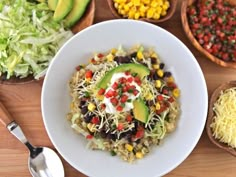 a white bowl filled with rice, beans and avocado on top of a wooden table