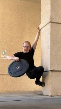 a man leaning against a wall with his arms in the air while holding onto a frisbee