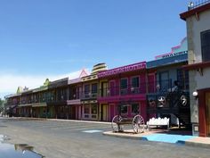 a row of multi - colored buildings on the side of a road with a horse drawn carriage parked in front