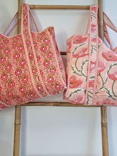 two pink bags sitting on top of a wooden ladder