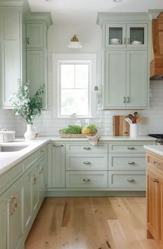 a kitchen with light green cabinets and wood floors