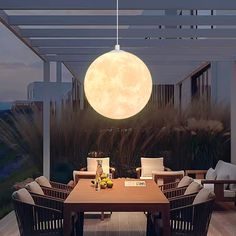 a dining room table with chairs and a large moon hanging from the ceiling above it