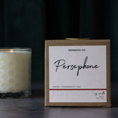 a candle sitting on top of a wooden table next to a box with the label cranberry cider