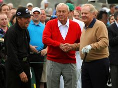 two men shaking hands at the end of a golf match as people watch from the sidelines