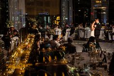 a group of people standing around in a room filled with tables and chairs at night